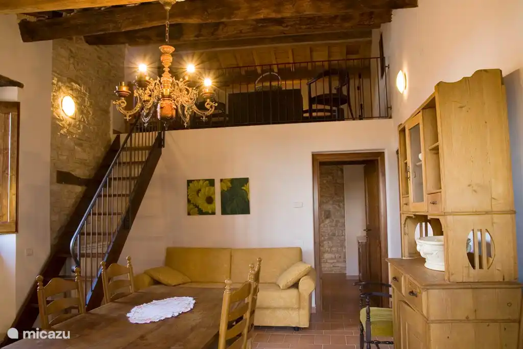Living room with dining table and sofa bed and open stairs to the loft