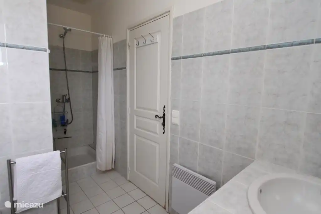 Das Badezimmer verfügt über eine Badewanne und eine Dusche sowie ein Waschbecken mit zwei Waschbecken.