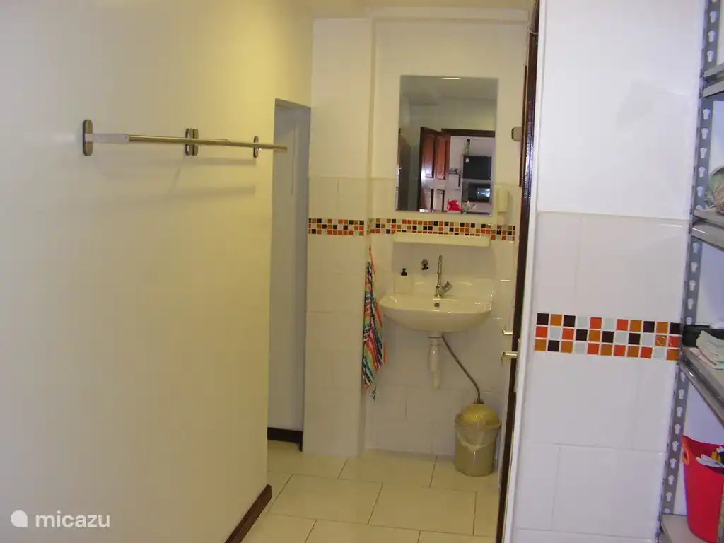 Cuarto húmedo visto desde la cocina. Toalleros a la izquierda y almacenamiento interior. Justo delante del lavabo. Cuarto de baño y ducha separados a la derecha. Inmediatamente a la derecha verás una parte de la estantería y encontrarás todo lo necesario para lavar y planchar.