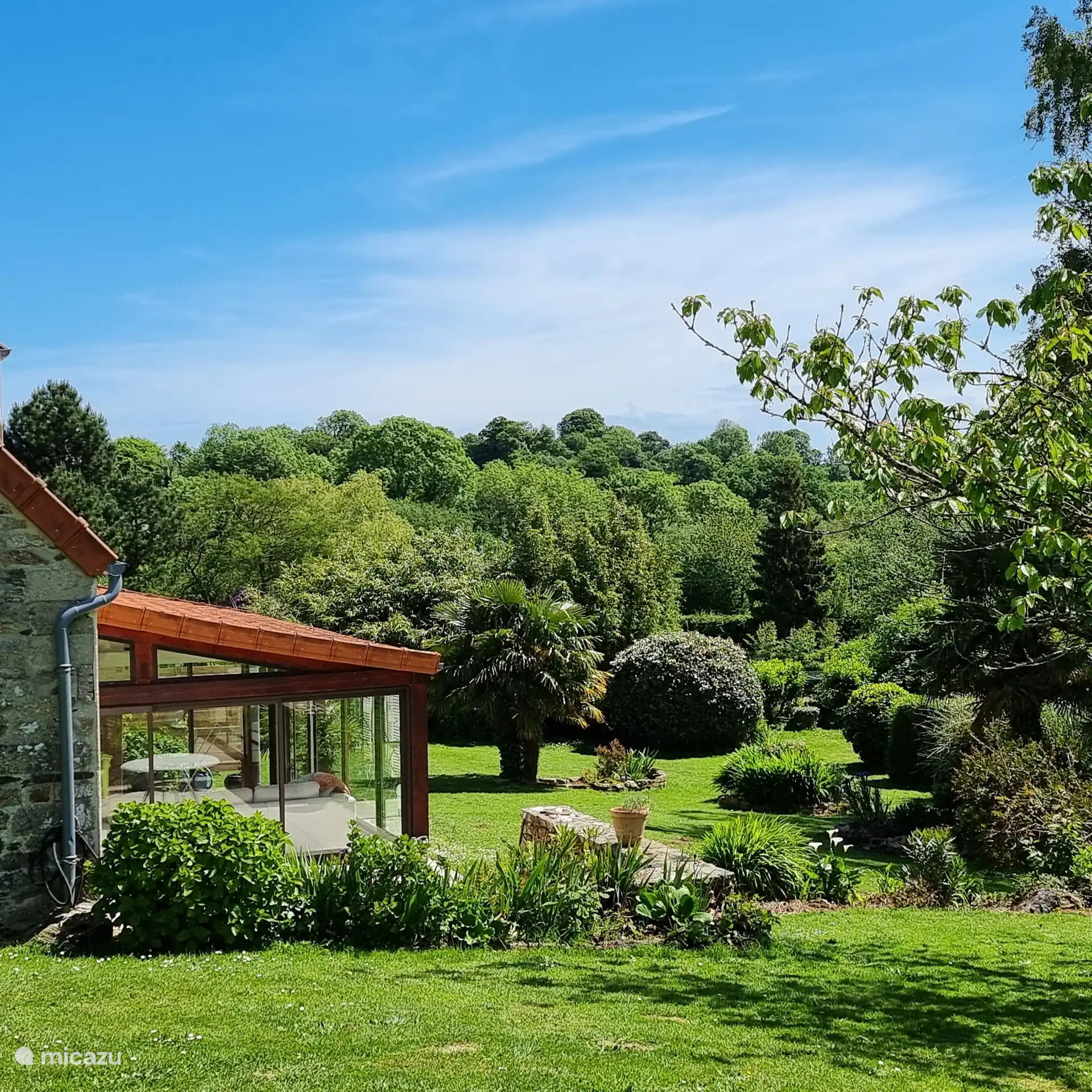 sonniger Wintergarten mit großem Ecksofa mit Terrasse und Grill