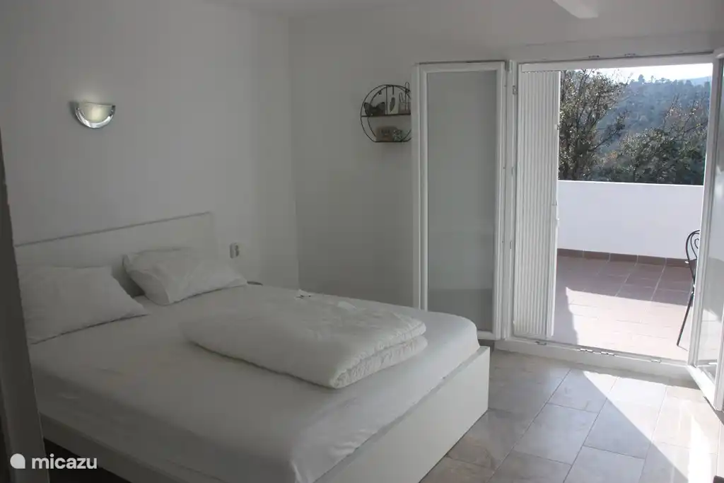 La chambre à l'étage avec lit double et grande armoire, avec balcon et coin salon