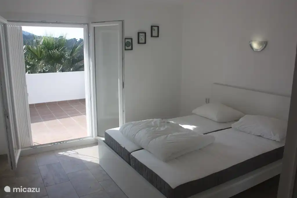 La chambre à l'étage avec lit double avec grande armoire, avec balcon et coin salon.