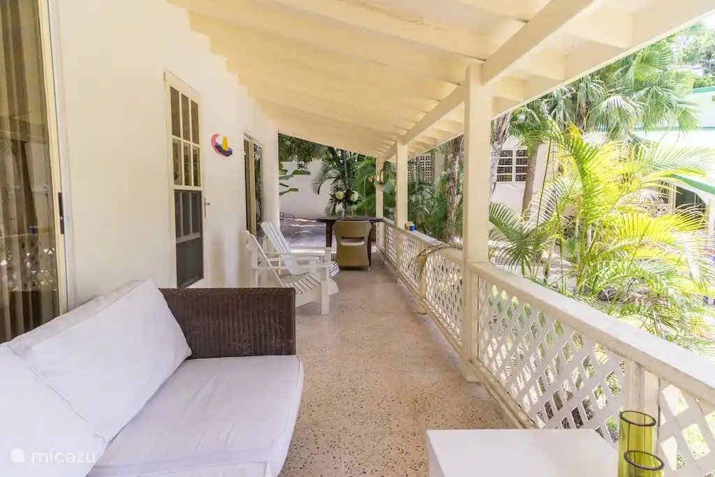 Porch at holiday home with comfortable couch, even more comfortable adirondack chairs and dining table