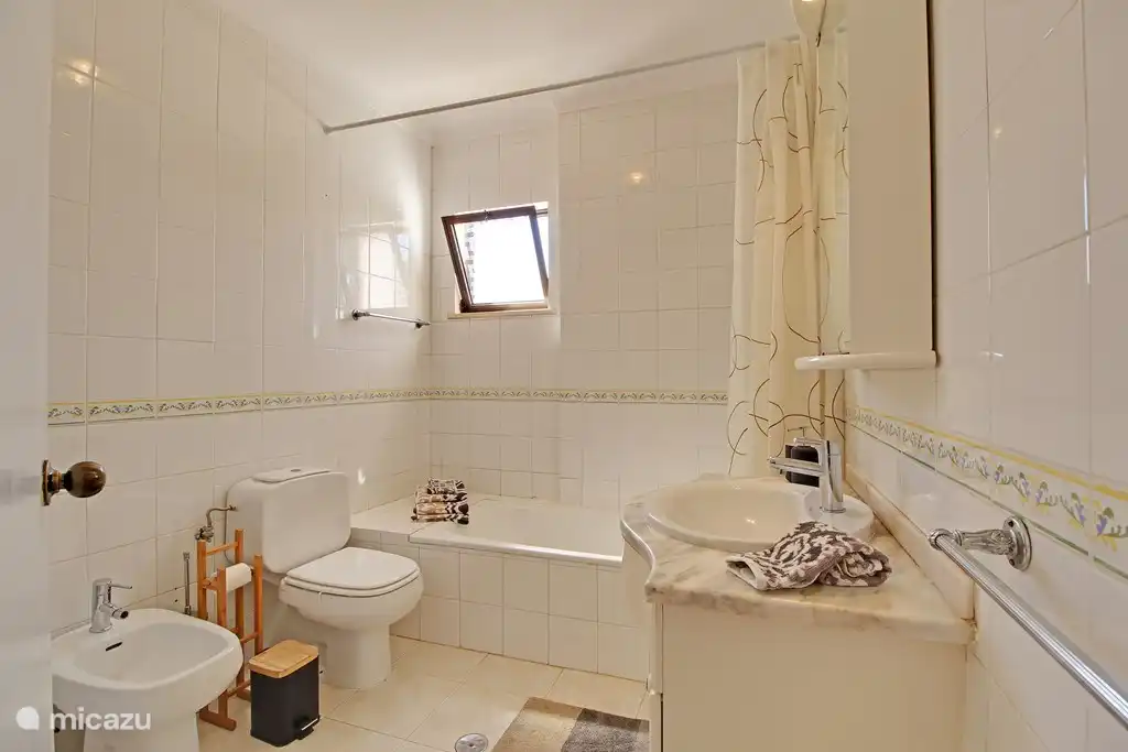La salle de bain avec baignoire / douche, WC, bidet et lavabo avec sèche-cheveux et prise.