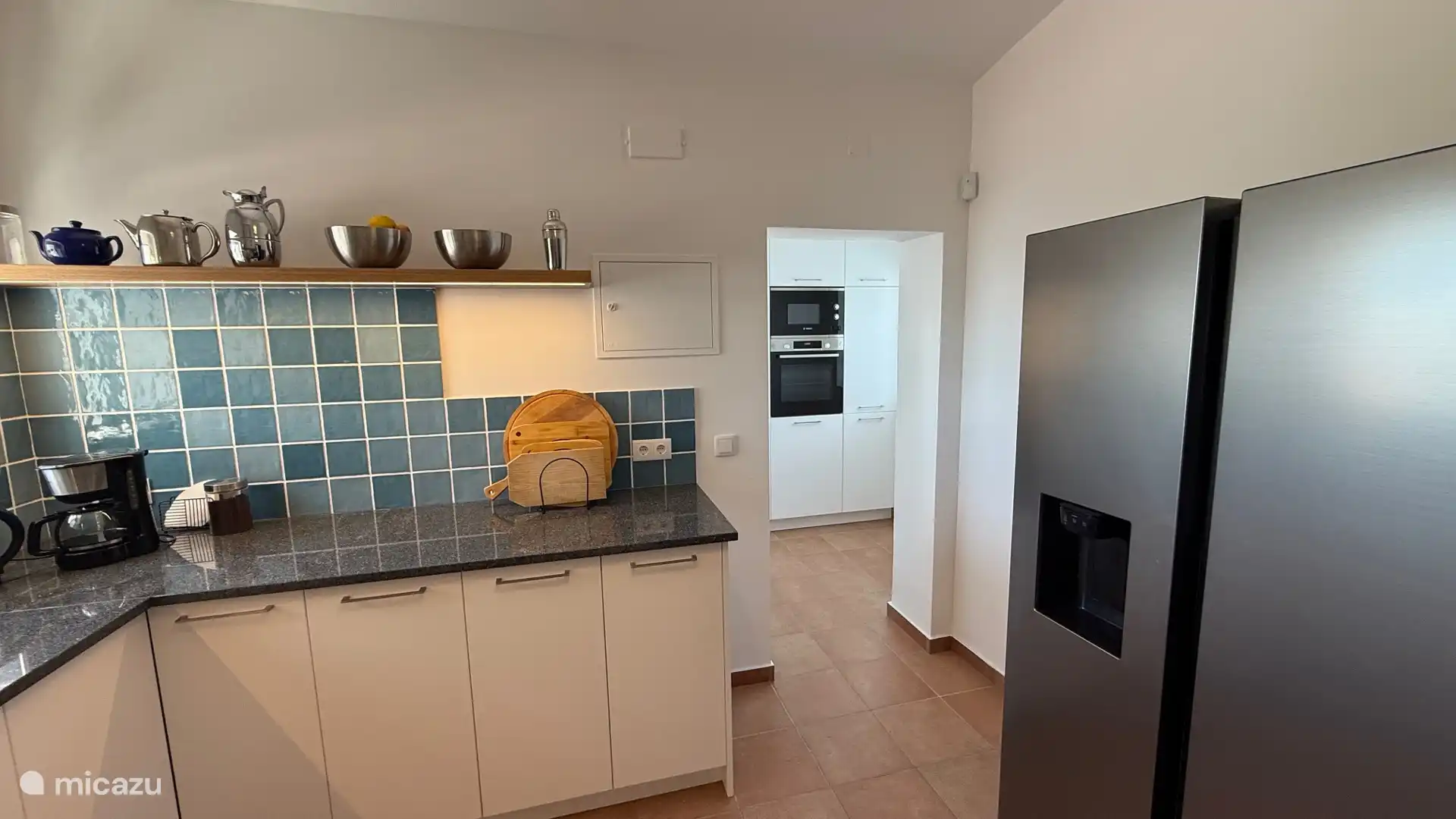 Doorkijk langs de amerikaanse koelkast met ijsblokjes machine naar de bijkeuken