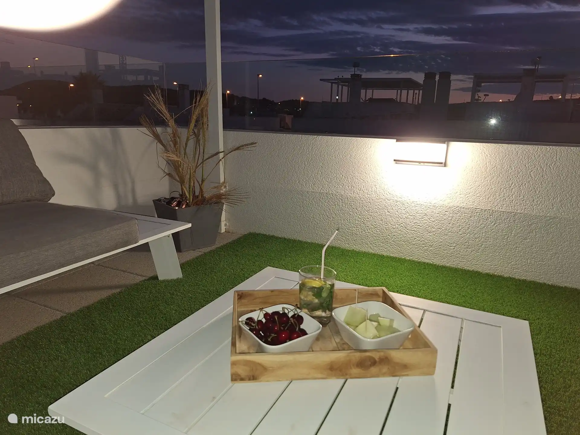 Salon confortable sur le toit-terrasse avec éclairage et gazon artificiel.