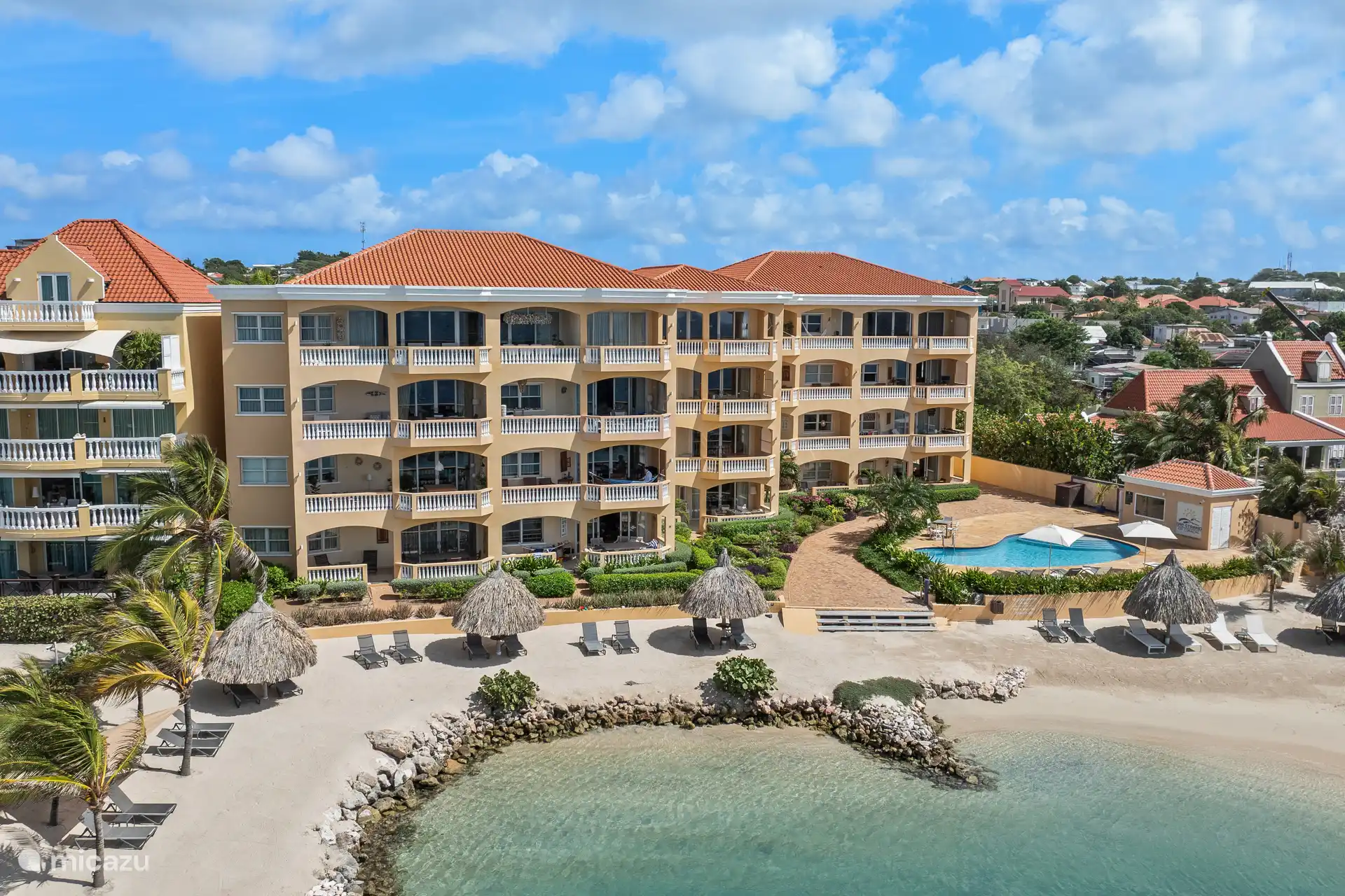 Der Apartmentkomplex Strand ist von einem schönen Garten und einem kinderfreundlichen Gemeinschaftspool mit Liegestühlen und Sonnenschirmen umgeben.