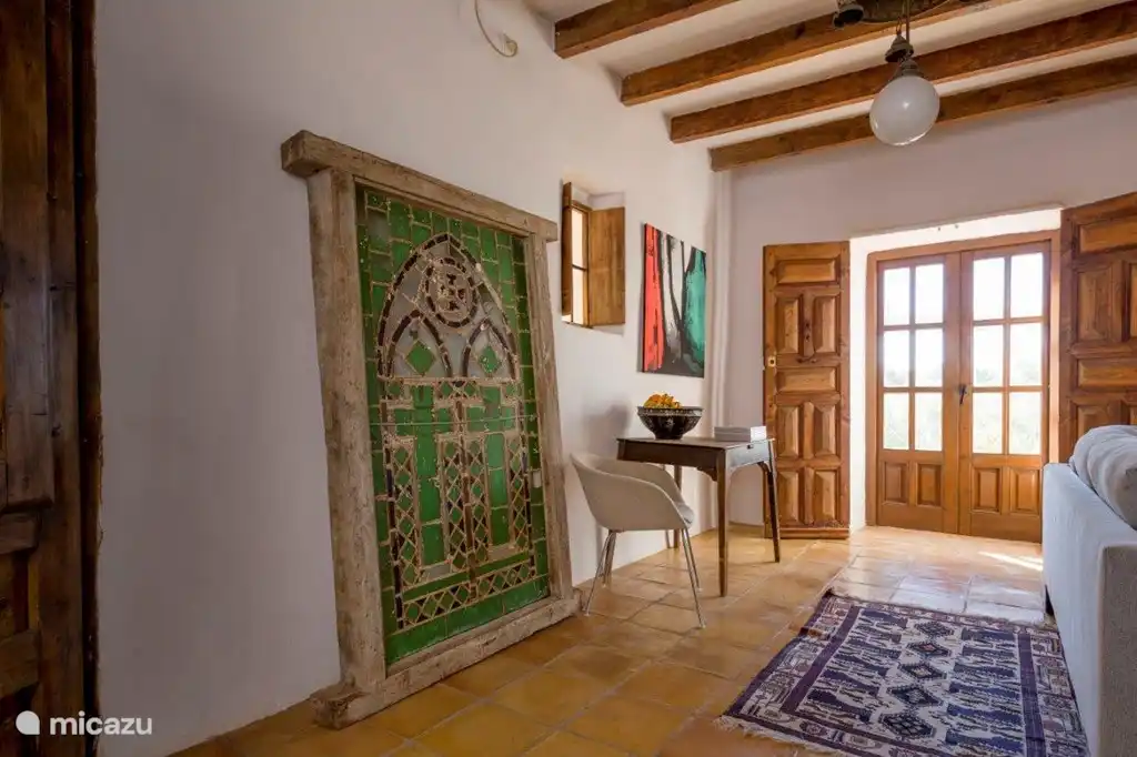 Wohnzimmer mit antikem Kirchenfenster und Türen zu einer Eckterrasse