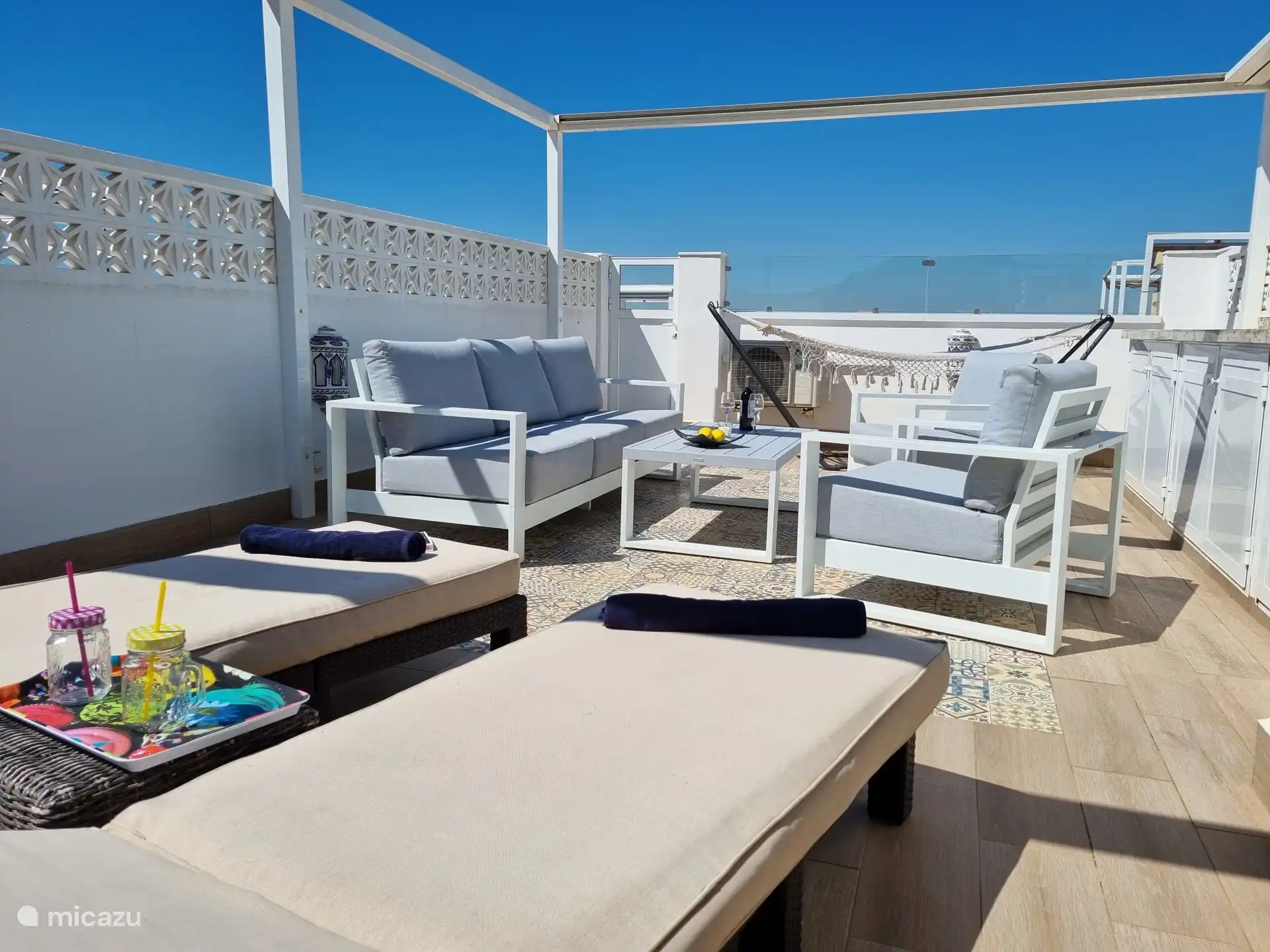 Wie schön ist es, auf der Dachterrasse zu entspannen! Eine Küche mit einem Kühlschrank, Markisen, einem luxuriösen Lounge-Set mit 2 Sonnenliegen und einer Hängematte ist ebenfalls vorhanden. Hier können Sie sich entspannen!  