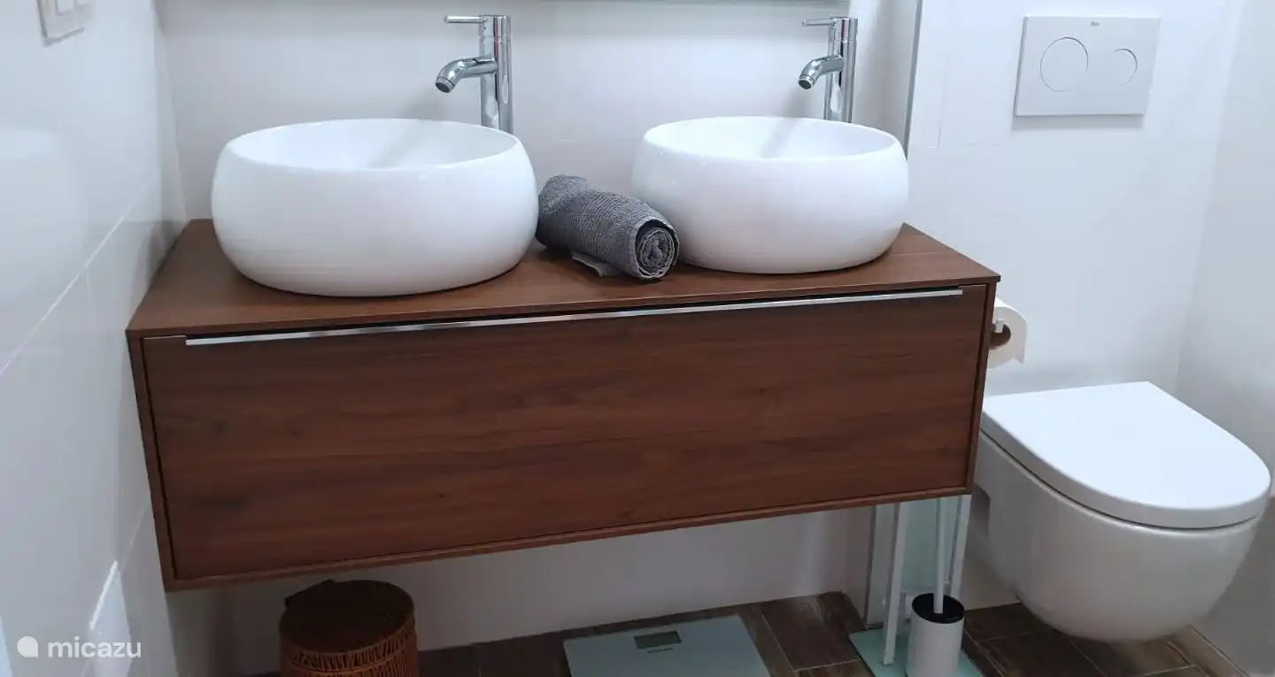 Das komplett renovierte Badezimmer verfügt über ein Doppelwaschbecken, eine hängende Toilette, eine ebenerdige Dusche und eine Fußbodenheizung.