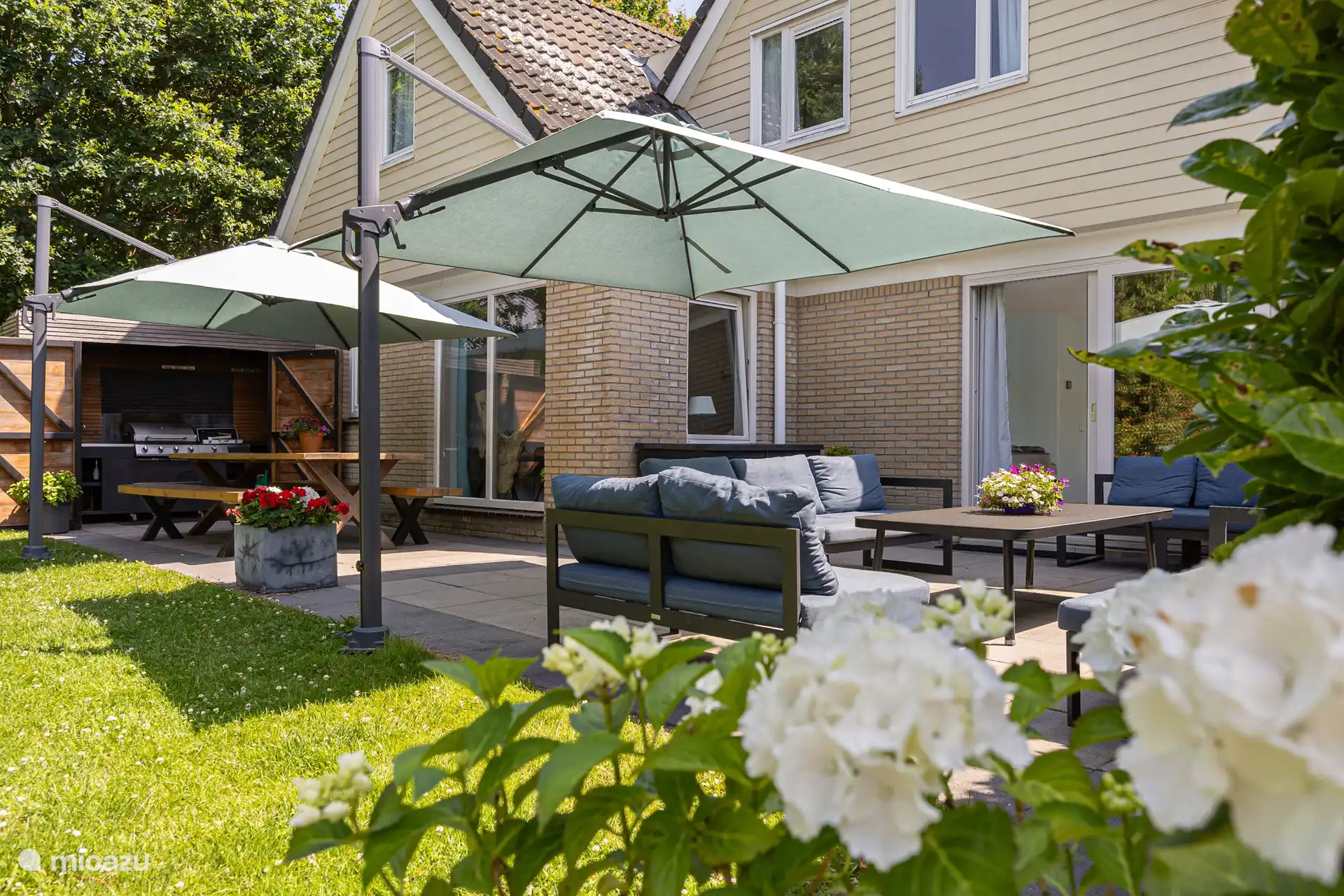 The outdoor kitchen with large dining table and the cozy sitting area on the terrace adjacent to the living room.