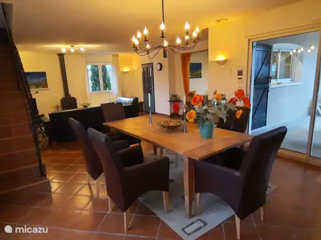 Pierradore **** en Francia, Hérault, Assignan - villa Zona de comedor con mesa grande con 6 sillas. Puertas correderas a la terraza y una escalera de piedra a la habitación de la torre con biblioteca y sofá cama. Enfrente, la entrada a la cocina abierta y la puerta al recibidor.