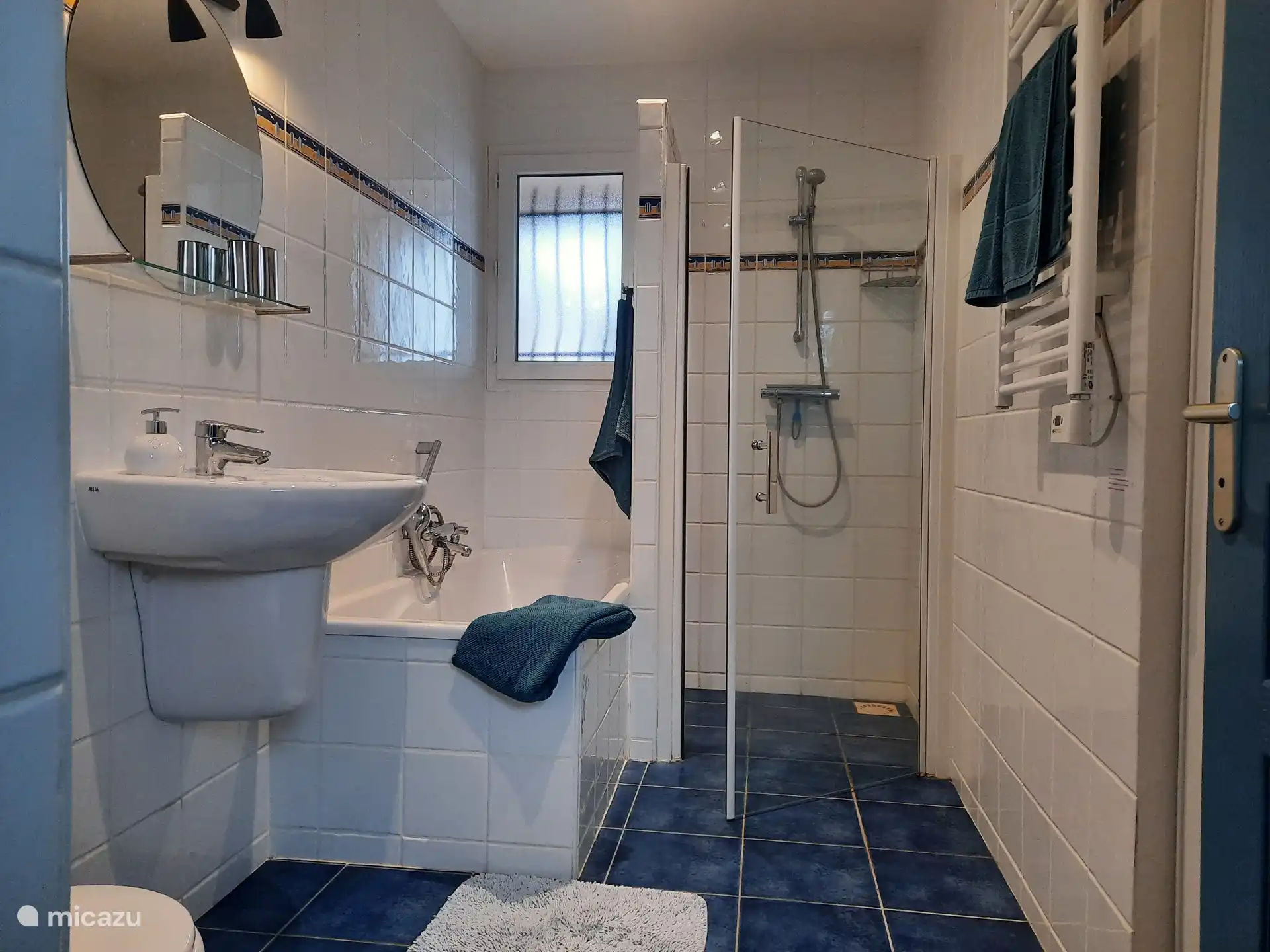 Badkamer 1 met inloopdouche, ligbad, wastafel en hangtoilet. De handdoekradiator dient tevens als kachel. Er is een ruime inbouwkast. De badkamer ligt tussen de living en de slaapkamers.