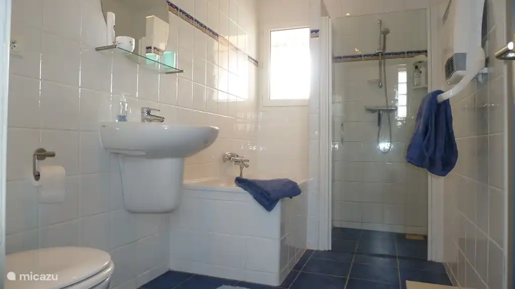 Salle de bain 1 avec douche à l'italienne, baignoire, lavabo et toilettes. La salle de bain a un radiateur électrique séparé. Cette salle de bain dispose également d'une grande armoire intégrée. La salle de bain est située à côté des chambres 1 et 2 et le couloir est séparé du salon par une porte.