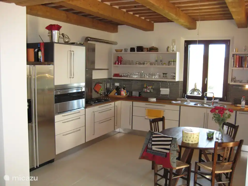 Een impressie van de uitgebreide keuken met grote oven, ruime ijskast en vriezer met ijsmachine, afwasmachine, magnetron, etc. Het klassieke plafond, bestaande uit balken en tegels is goed zichtbaar.