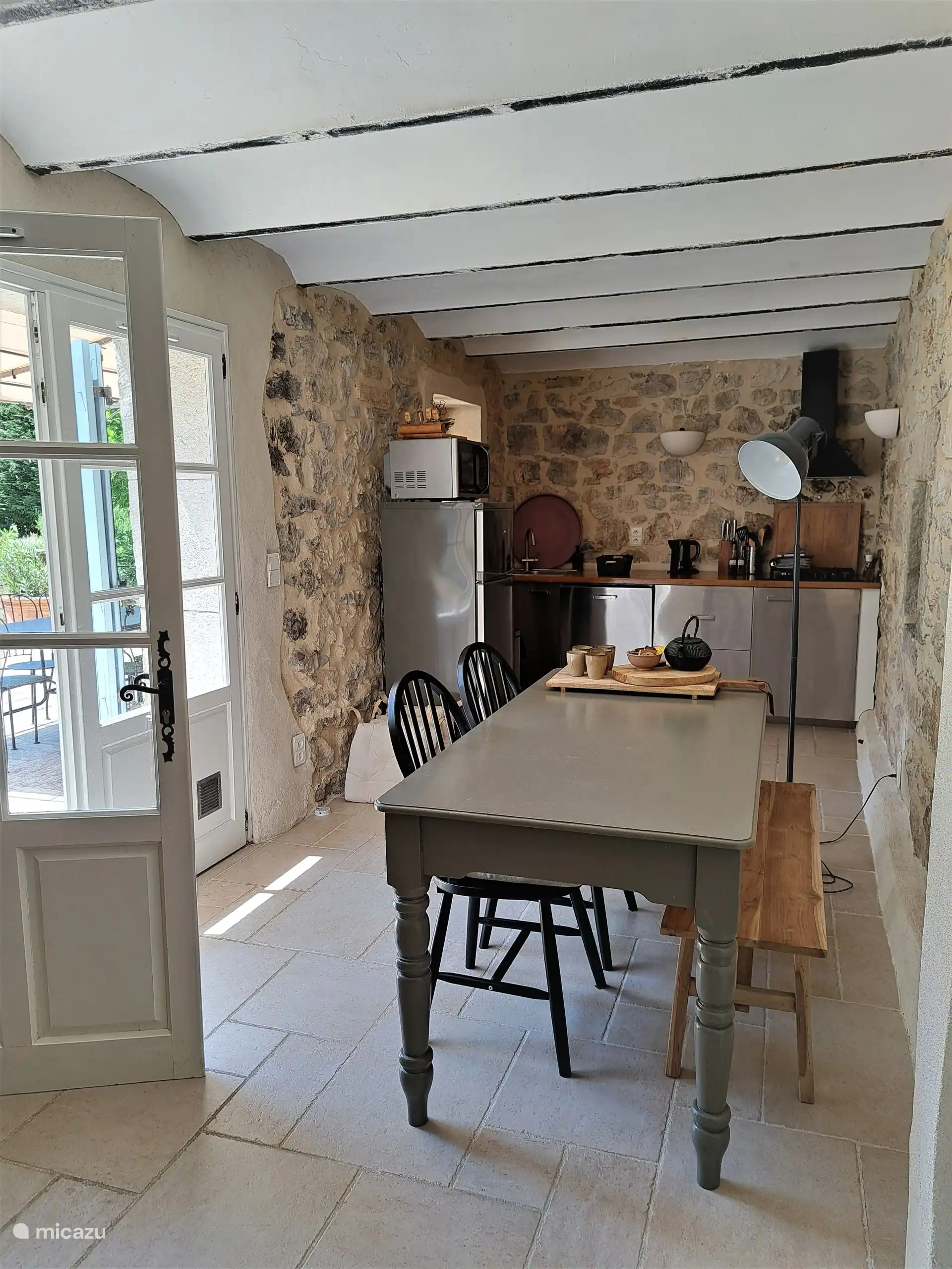 Cuisine avec portes-fenêtres donnant sur la terrasse où se trouve un ensemble à manger.