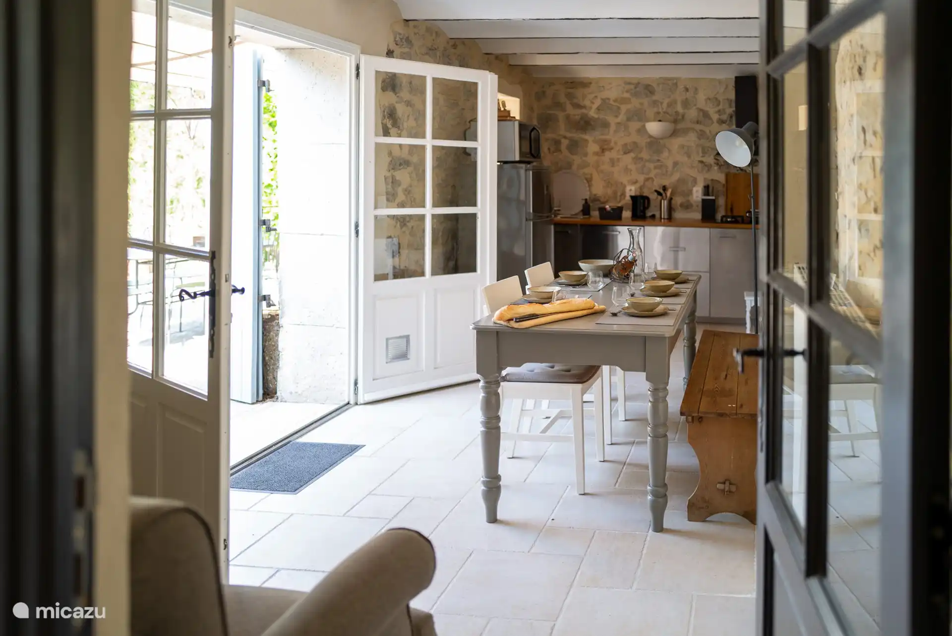 Cuisine-salle à manger avec coin repas, cuisine, vaisselier et fauteuil.