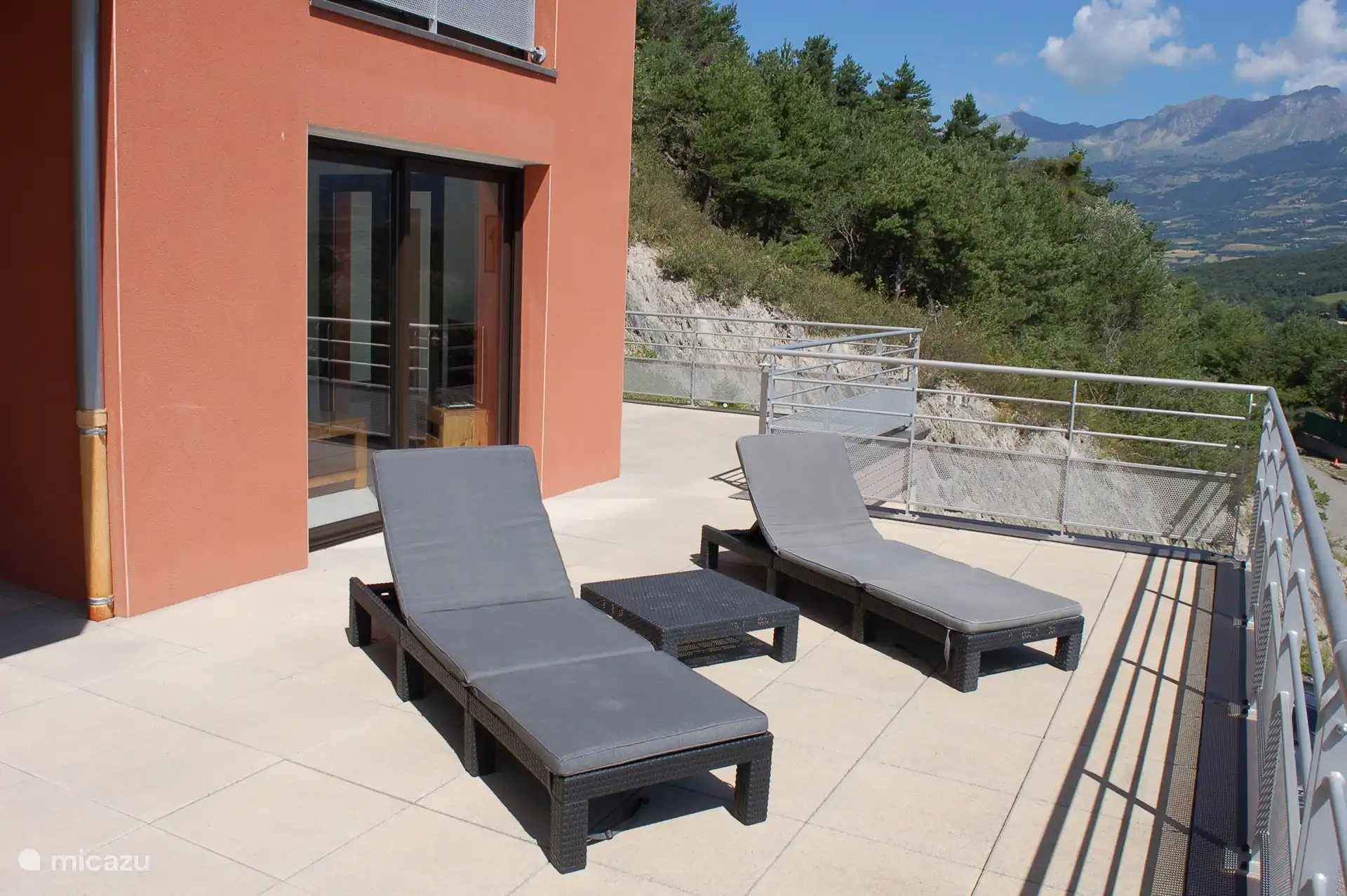 Balkon mit Sonnenliegen und Blick auf See und Wald