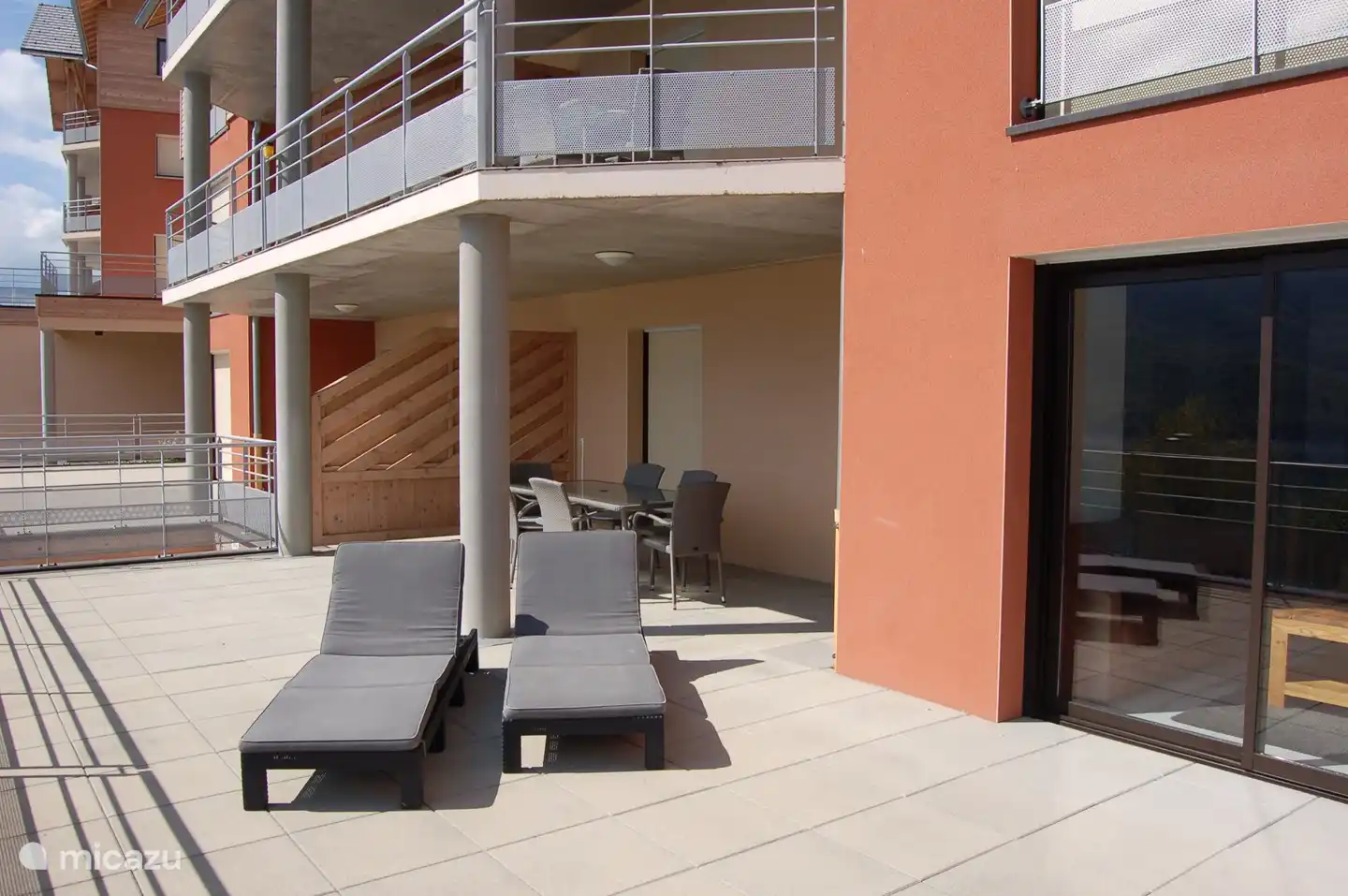 großer Balkon mit großem Tisch und Sonnenliegen