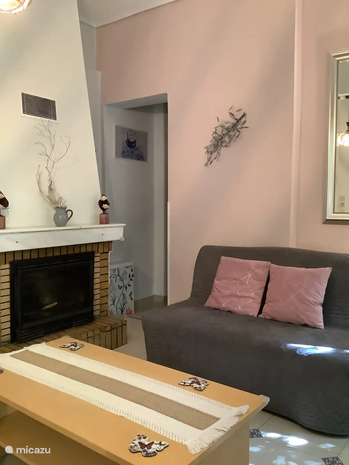 De woonkamer met een kijkje op de haard en het halletje