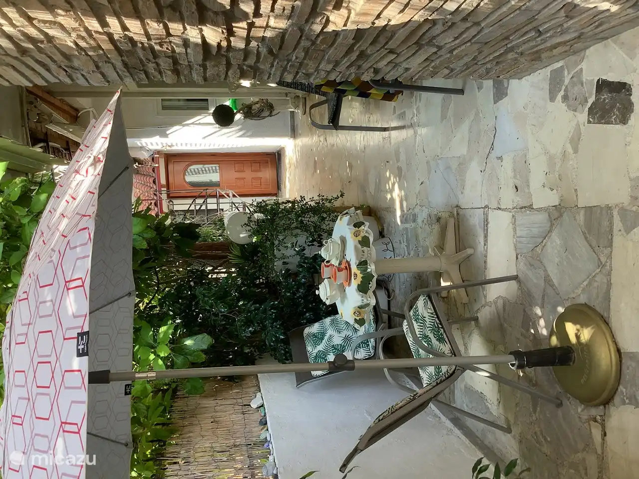 De zithoek op het terras met zicht op de ingang en de wenteltrap naar het dakterras