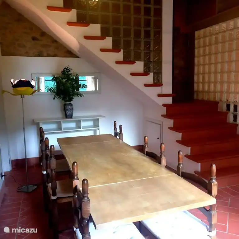 Dining table and stairs to upstairs bedrooms. In the far left corner there is a door to the fourth bathroom,  with shower, basin and WC.