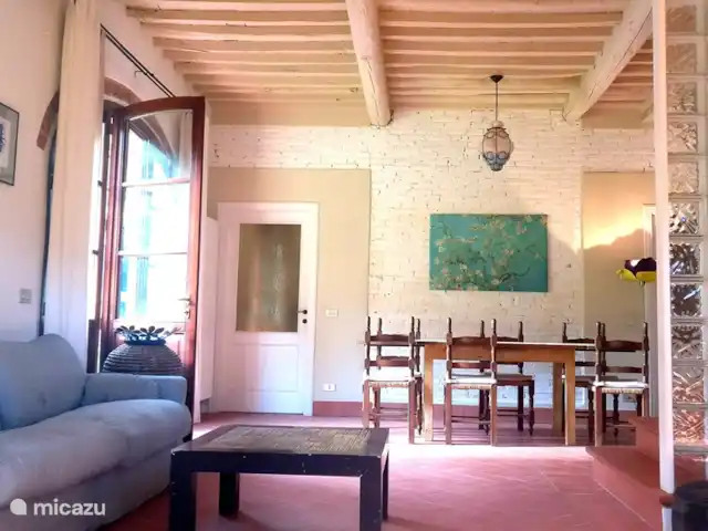 Location de Vacances Italie, Toscane, Lucca, villa - Grange toscane rustique La salle à manger/salon a trois portes avec de grandes fenêtres, orientées ouest, menant au jardin avec un espace privé avec table à manger.