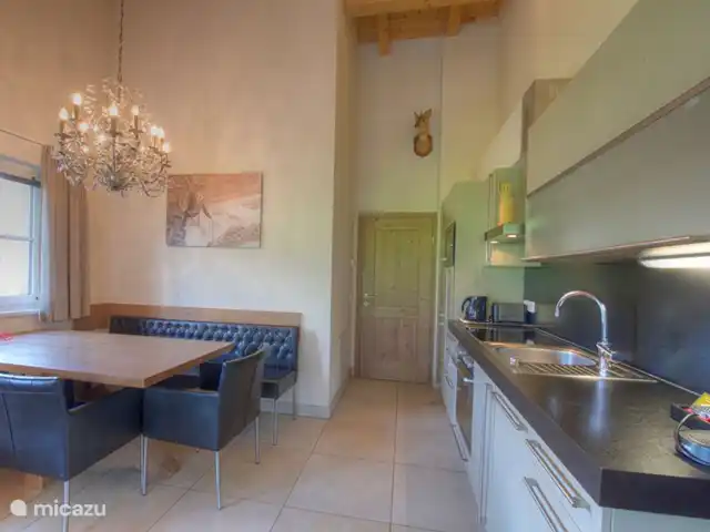 Resort de montaña Kaprun TopE20 en Austria, Salzburgo, Kaprun - apartamento Una hermosa cocina abierta es el lugar perfecto para preparar deliciosas comidas. La mesa del comedor está cerca, para que todos puedan admirar sus habilidades culinarias mientras disfrutan de una copa de vino.