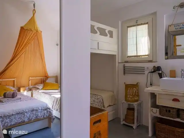 Leontine's Lodge in Sardinië huren in Italië, Sardinië, San Pantaleo - bungalow Blik in de spiegel van de familiekamer om aan te geven hoe de bedden zich ten opzichte van elkaar verhouden. Deze kamer heeft de badkamer bereikbaar via de gang met regendouche, wc met sproeikraan en wastafel, een extra buitendouche in de tuin ervoor en een extra wastafel in de kamer.