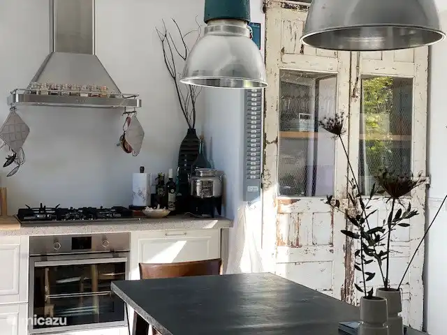 Die helle Küche ist mit allerlei modernen Geräten ausgestattet, hat aber viele coole Materialien mit Vintage-Funden wie den alten weißen Türen aus Katalonien