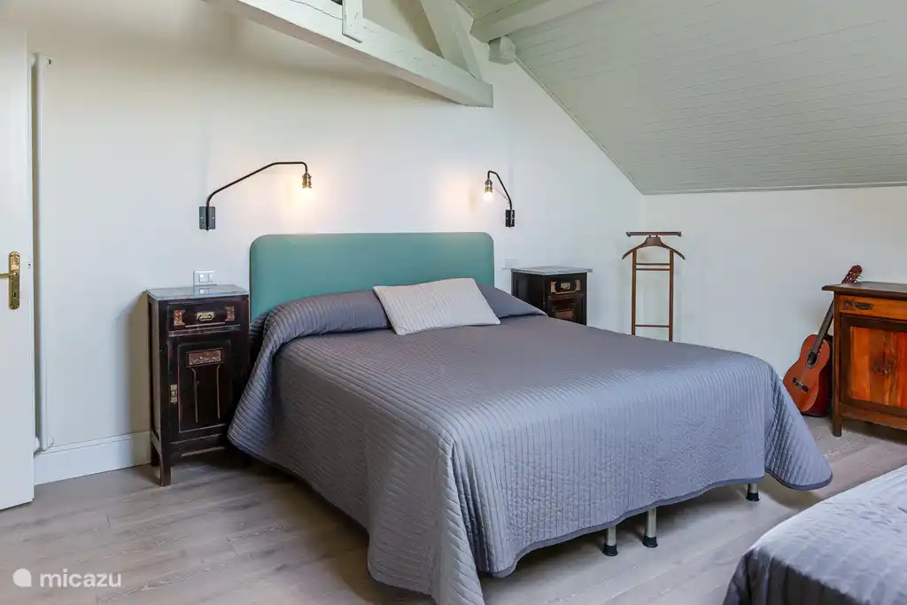 Dormitorio con una (1) cama doble y una (1) cama individual. Mezcla de muebles antiguos y modernos, claraboya con vista a los árboles altos del jardín