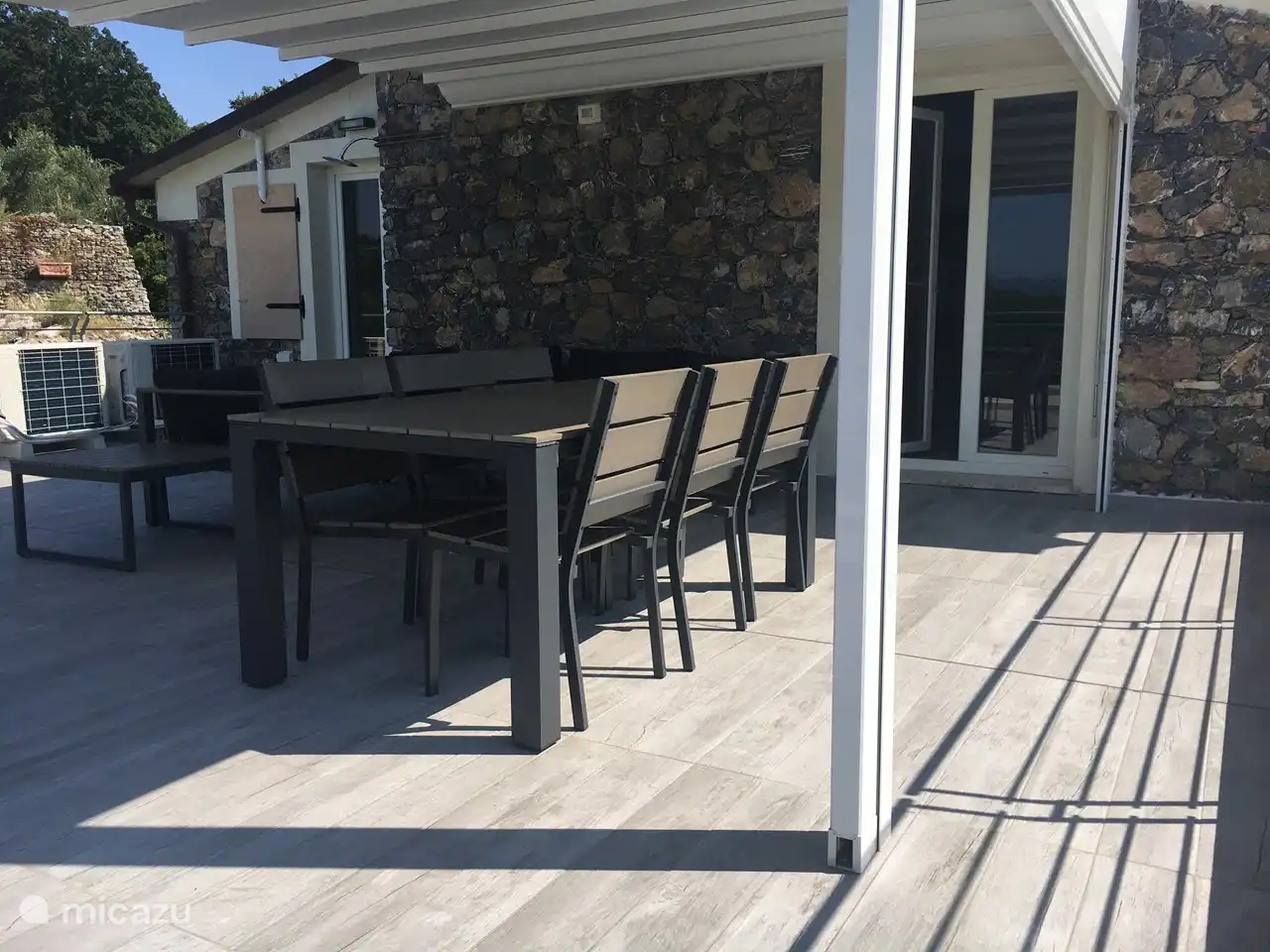 Terrasse mit Esstisch und Gartenmöbeln