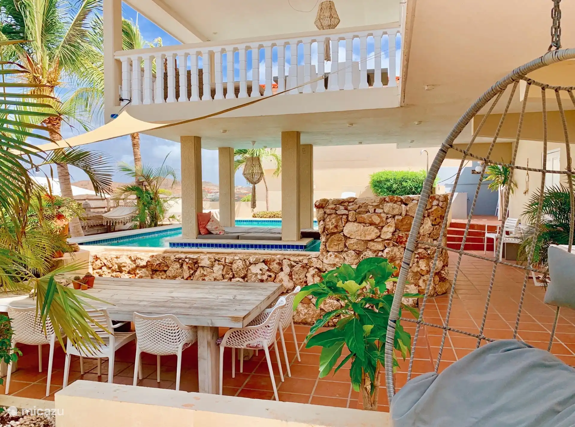 La mesa comunitaria exterior en el jardín con piscina.