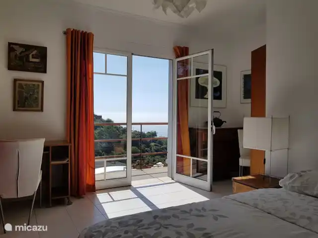 Raposeira de São João | Portugal, Madère, Calheta - villa chambre 1, portes-fenêtres donnant sur le balcon, le coin travail à gauche et la commode à droite des portes
