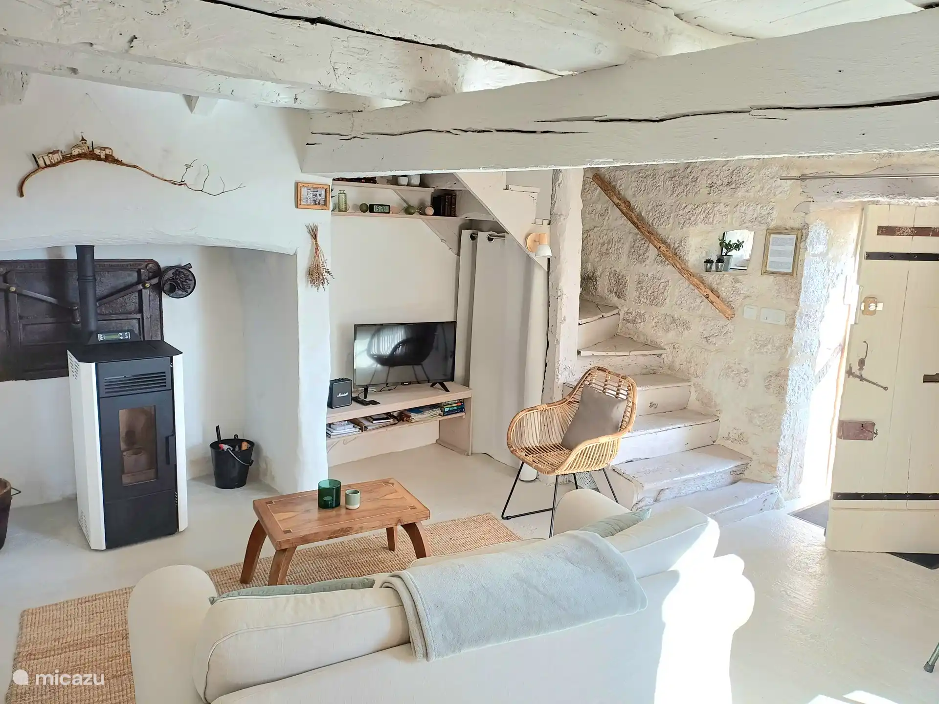 Wohnzimmer mit Pelletofen, Smart-TV, Treppe und Eingang.