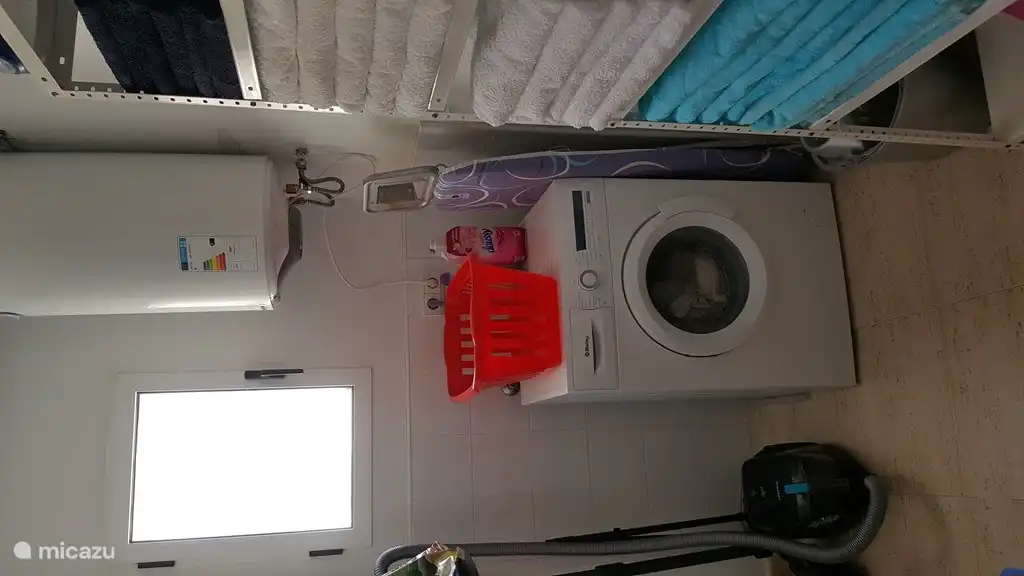 Waschmaschine in separatem Raum mit schönen Handtüchern und Strandtüchern