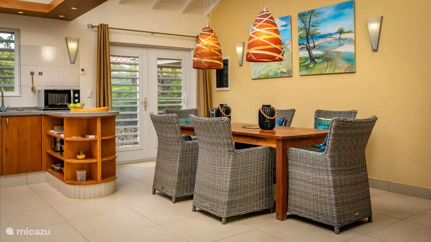 Wilt u een keer afwisselen met dineren , dan heeft ook de woonkamer een royale eethoek met 6 rieten stoelen. De mozaïk hanglampen geven een sfeervol effect