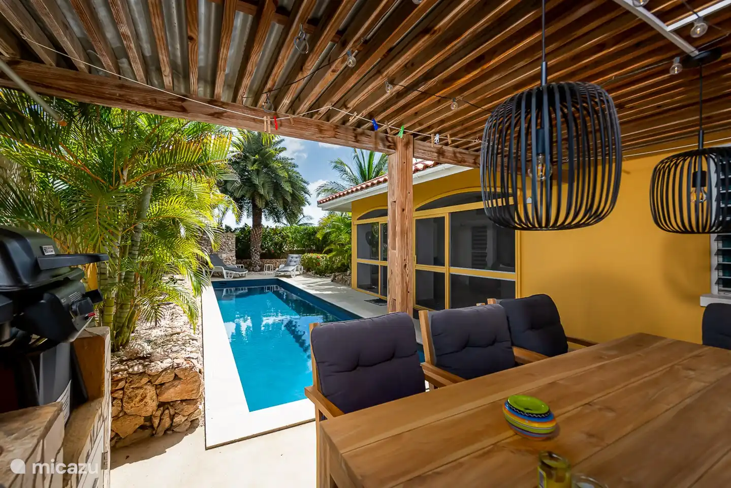 teakhouten eettafel met 6 stoelen met kussens en sfeervolle  hangverlichting om uw barbecue tot een succes te maken