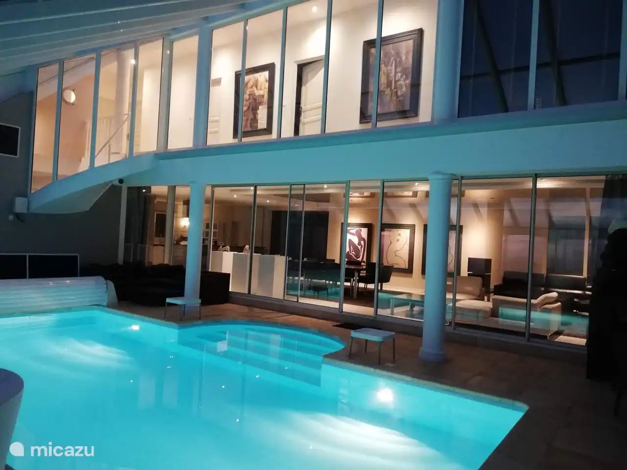 Swimmingpool mit Blick auf den Wohnraum mit Abendbeleuchtung