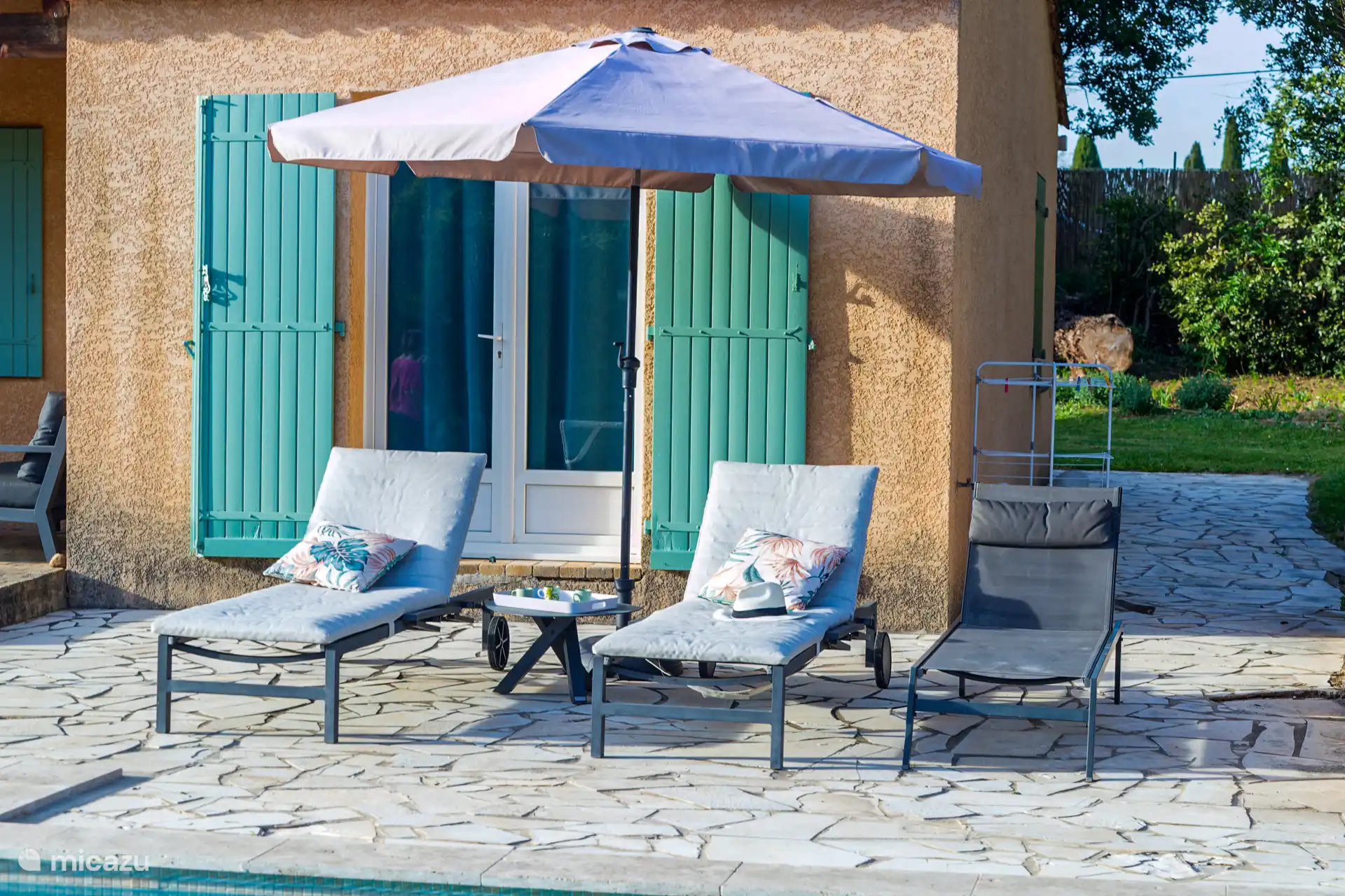 Leg dich unter den Sonnenschirm auf die Sonnenliege am Pool