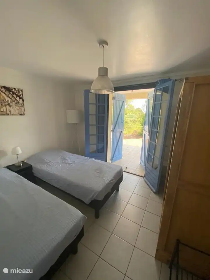 Schlafzimmer mit zwei Einzelbetten, Klimaanlage, Kleiderschrank und Terrassentüren zum Garten.
