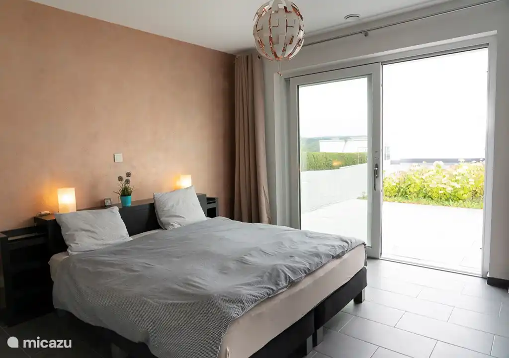 Gastenslaapkamer 2 met openslaande deuren uitkomend op terras en tuin 