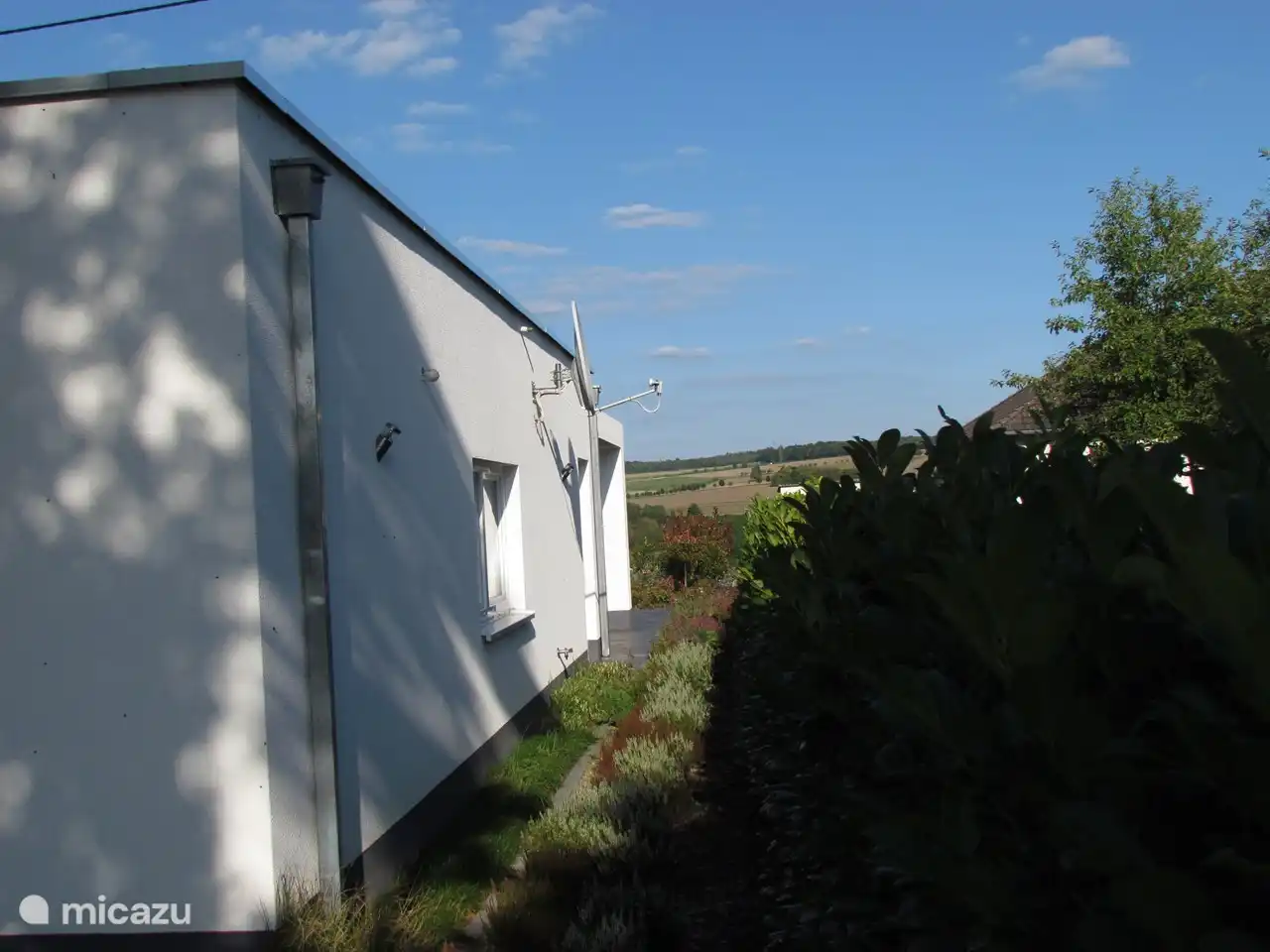 De Zuidzijde van de woning met slaapkamer en uitzicht vanaf buitenterras