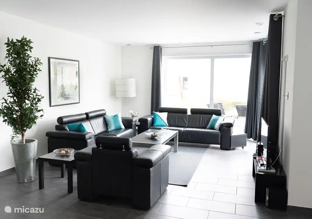 De woonkamer met aangrenzend serre, terras, tuin en open keuken