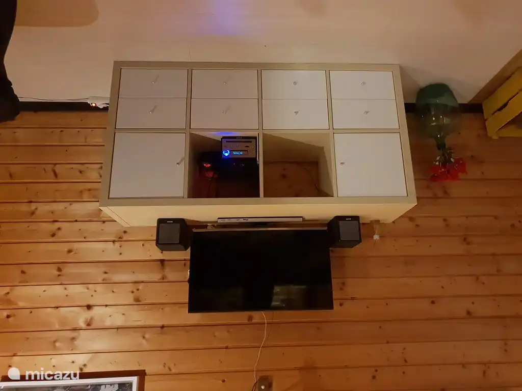 Un mueble de TV con reproductor de DVD. Los cajones contienen varios DVD con diferentes géneros.