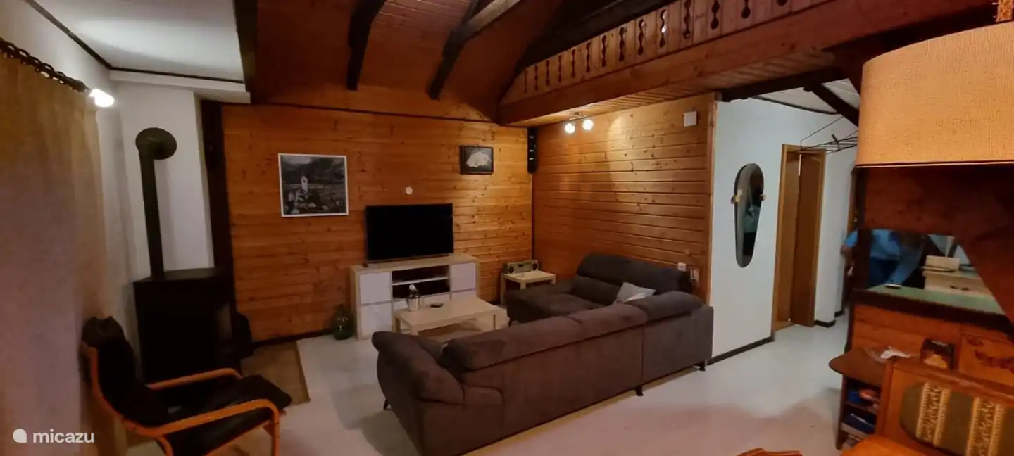 Habitación con sofá rinconera, TV y estufa de pellets