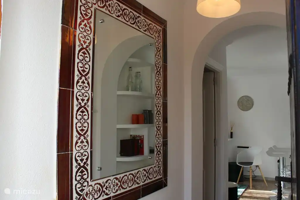 El pasillo con espejo y puerta al dormitorio.