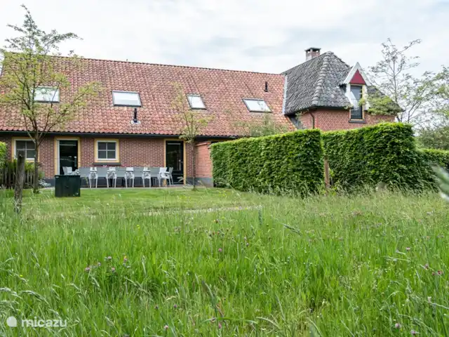 Le garde-frontière | Pays-Bas, Gueldre, Aalten - maison de vacances Façade latérale de l'ancienne ancienne ferme, rénovée et aménagée en gîte de groupe spacieux, agréable et confortable. Derrière la haie hébergement 't Woonhuus
