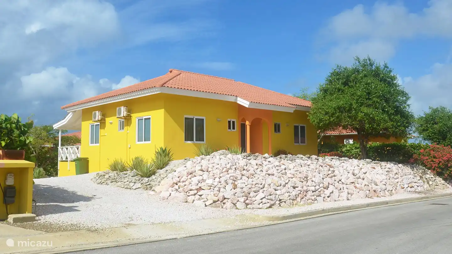 Vue latérale depuis la route. La villa est sur un terrain surélevé pour plus d'intimité.
