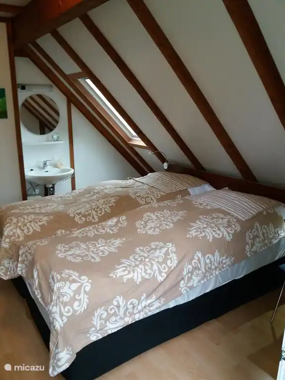 De slaapkamer op de tweede verdieping is voorzien van een wastafel met warm en koud stromend water